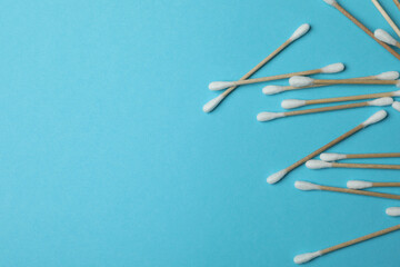 Cotton swabs on blue background, space for text