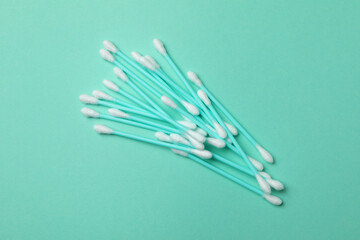 Plastic cotton swabs on mint background, space for text