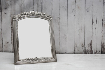Elegant photo frame without photo in silver color. The background is made of wood