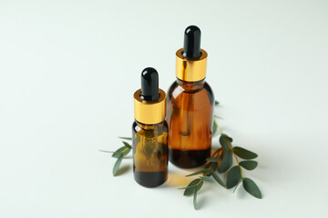 Brown bottles of eucalyptus oil and twigs on white background