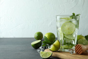 Board with glass of mojito cocktail and ingredients, space for text