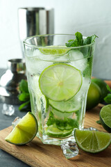 Board with glass of mojito cocktail and ingredients, close up