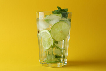 Glass of mojito cocktail on yellow background