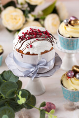 Spring Easter cake with white icing and sugar decor, easter cupcakes  and easter eggs on the  white table.  Easter concept