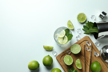 Glass of fresh mojito cocktail and ingredients on white background