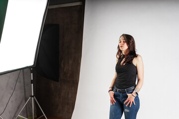 Alternative model with tattoos and jewelry poses in a professional photo studio with spotlights