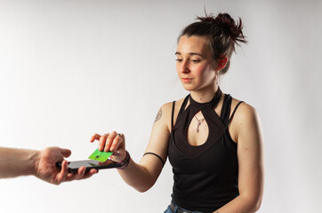 Alternative young woman with tattoos paying with her contactless credit card via mobile phone