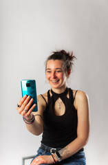 Alternative young woman with tattoos making a video call with her mobile phone.