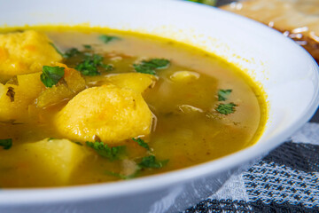 Delicious matzo ball or kneidlach soup. Jewish traditional cuisine, homemade gluten free version. Hot and comforting matzah ball soup with vegetables and root veggies. Matzos in background. Closeup