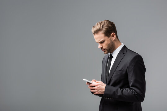 serious businessman chatting on mobile phone isolated on grey