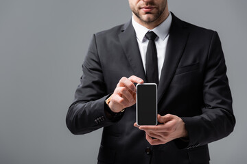 cropped view of businessman showing smartphone with blank screen isolated on grey