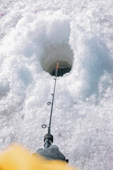 Ice fishing. Seasonal hobby. Hand holds a fishing rod for ice fishing. Vertical shot