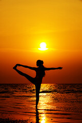 Fototapeta na wymiar silhouette of woman doing yoga on the beach at sunset 