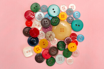 Buttons for clothes on a pink colored background. Sewing accessories.