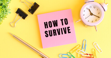 Pink paper with the text HOW TO SURVIVE. Clock, pen on a yellow background.