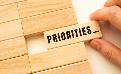 Hand holds a wooden cube with the text PRIORITIES.