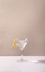 Glass of lemon drop martini cocktail on table against grey background