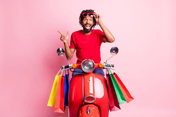 Photo of young black man dreadlocks surprised sale black friday shop bag point finger empty space promo isolated over pink color background