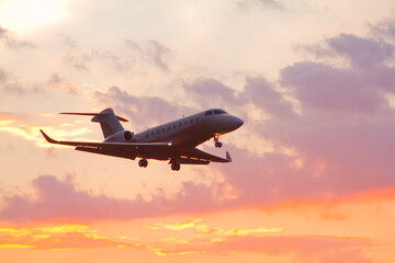 Fototapeta na wymiar Private twin-engine jet aircraft landing at the airport with landing gear and flaps extended at sunset