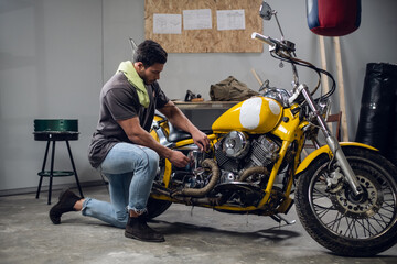 A young mechanic tuning a motorcycle in an auto repair shop. Hobbies and work activity.