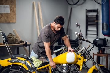 Fototapeta na wymiar A young mechanic tuning a motorcycle in an auto repair shop. Hobbies and work activity.