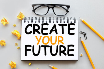Create Your Future . text on white notepad paper. near the crumpled yellow stackers on a gray...