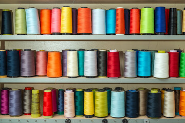 Colorful sewing tread bobbins with lined up on the shelf