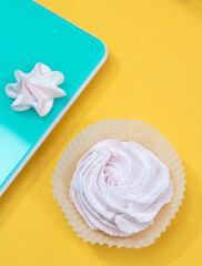 On a yellow background is a pink marshmallow, on a mint background is a meringue. Selective focus.