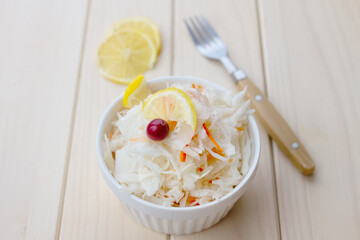 sauerkraut with cranberries and lemon, metal fork on light wooden table