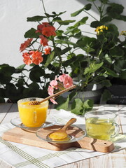 Rustic natural yellow honey from a private apiary against the backdrop of flowering plants. The idea of the benefits of honey.