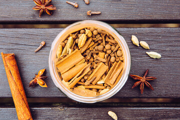 Various homemade chai tea ground ingredients in glass jar, flat lay view. Green cardamom pods,...