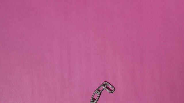 Chain heart, stopmotion. Pink background. Unchain my heart. Strong love. Steel chain in form of heart.