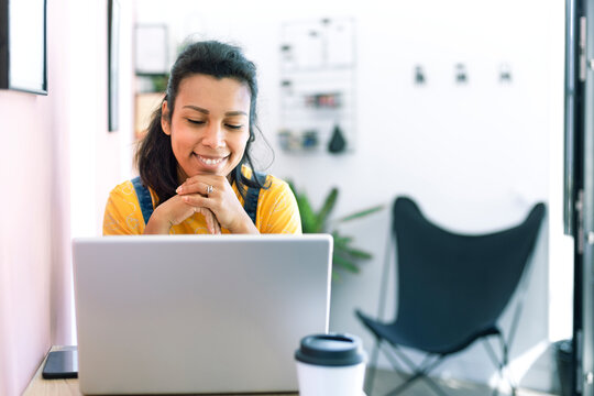 Young Latina Woman Using A Laptop At Her Workplace. Space For Text.