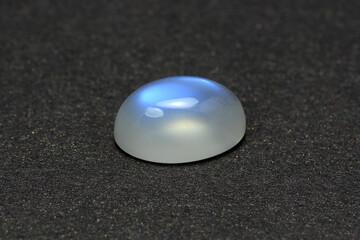 Natural adularia blue sheen oval shaped cabochon moonstone. Loose gem on gray textured leather...