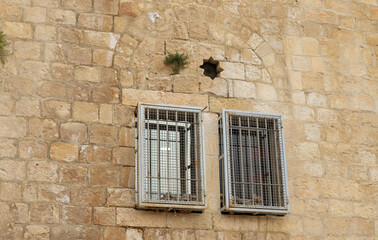 Fototapeta na wymiar Windows with metal bars on the facade of an old building in the old city of Jerusalem, Israel