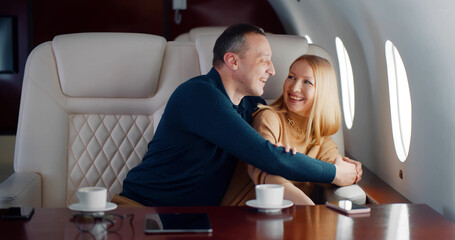 Happy middle-aged couple laughing and enjoying view in airplane window