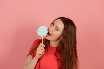 A girl with a candy in her hand on a pink background