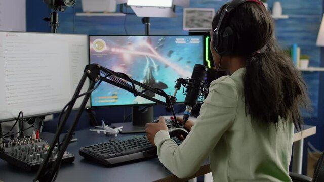 Streamer cyber performing space shooter video game holding controller on RGB powerful computer talking with players on stream chat and microphone during professional competition. Player man streaming