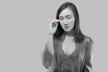 Asian women have rubbing in the eye. Have itching in the eye. Female in the satin red nightgown and...