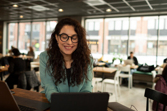 Smiling woman using laptop in cafe