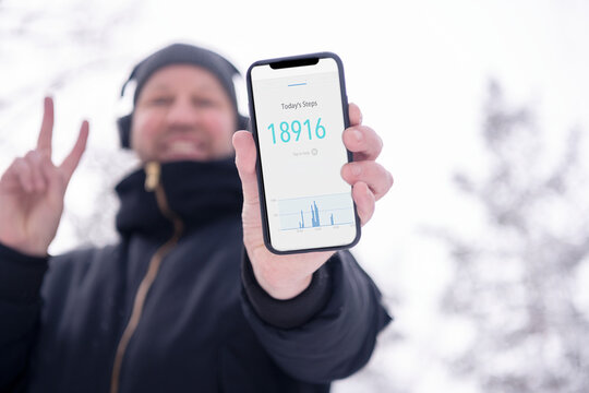 Man holding smart phone and showing step tracker