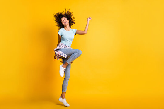 Full length photo of cute adorable dark skin wavy lady wear blue t-shirt dancing empty space isolated yellow color background