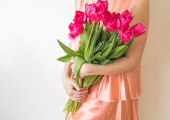 Beautiful young girl in dress holding big bouquet of tulips isolated over white background
