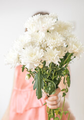 Faceless concept. Beautiful young woman with chrysantemas  bouquet. Spring portrait. Bright white flowers in girl's hands.