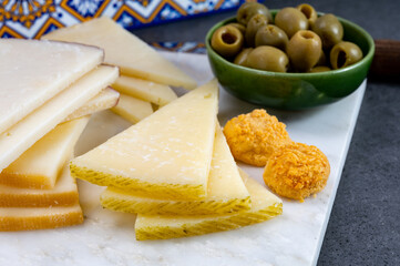 Spanish snacks tapas, variety of sliced goat, sheep, manchego cheeses, green olives