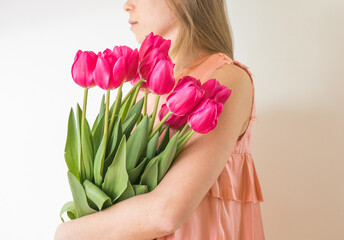Beautiful young woman with tulip bouquet. Spring portrait. Bright pink flowers in girl's hands.