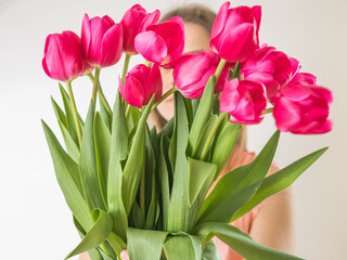 Faceless concept. Beautiful young woman with tulip bouquet. Spring portrait. Bright pink flowers in girl's hands.