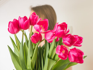 Faceless concept. Beautiful young woman with tulip bouquet. Spring portrait. Bright pink flowers in girl's hands.