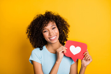 Photo of cute adorable dark skin wavy lady wear blue t-shirt holding red like sign isolated yellow...