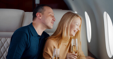 Mature successful couple drinking champagne and looking through private jet window © nimito